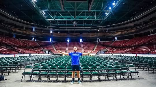 Brian Rand with arms wide open in an empty arena before a live event